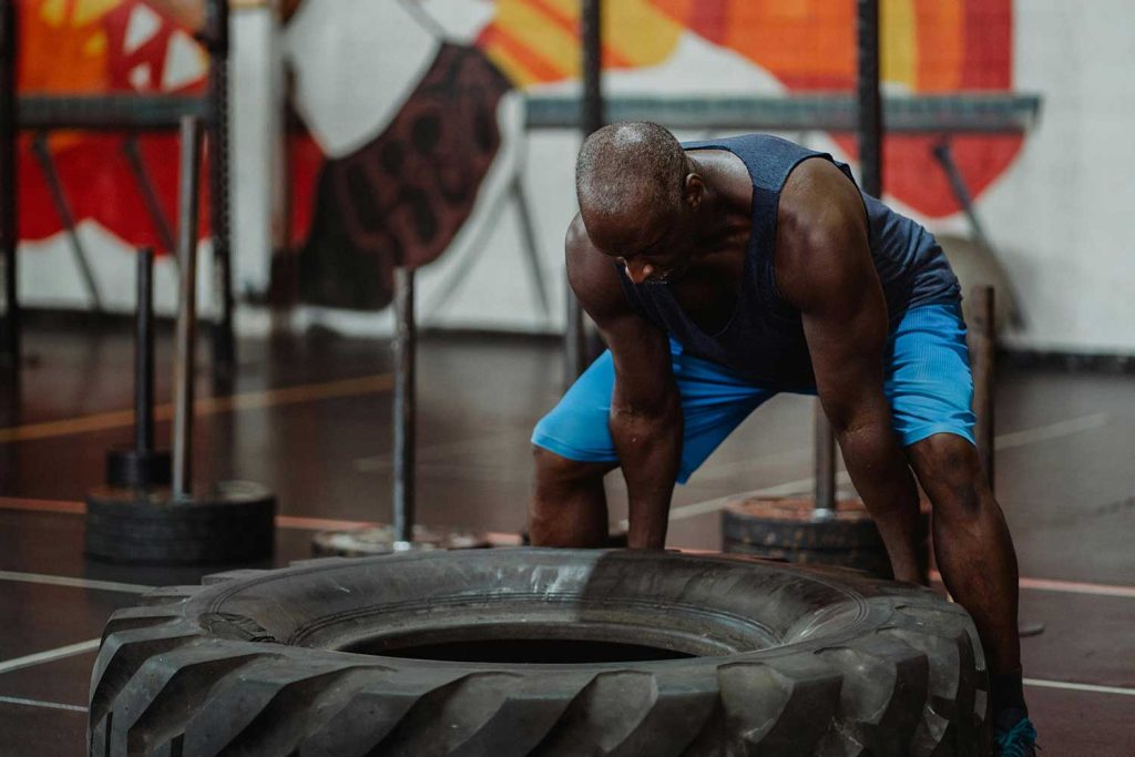 Man lifting tire inside gym